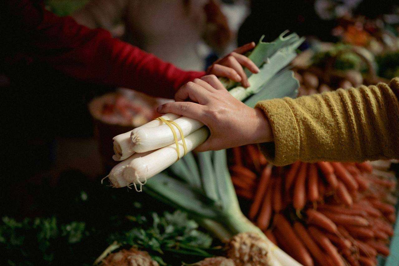 Two people exchanging a bunch of leeks at a market