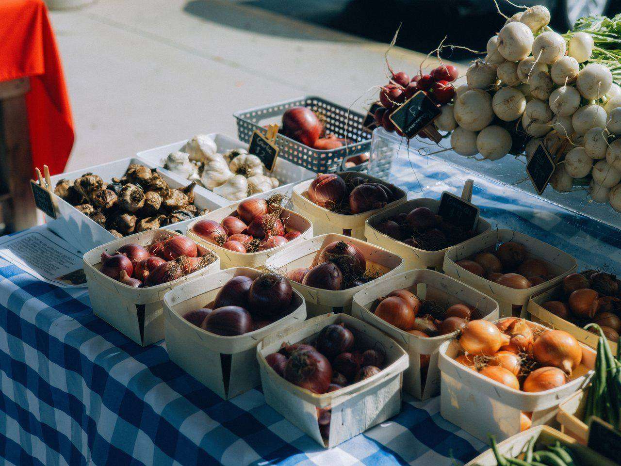 Farmers market table with baskets of onions and garlic
