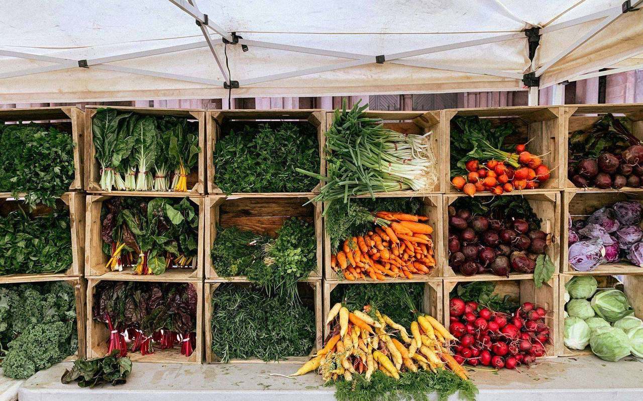 Farmers market crates of greens carrots and beets