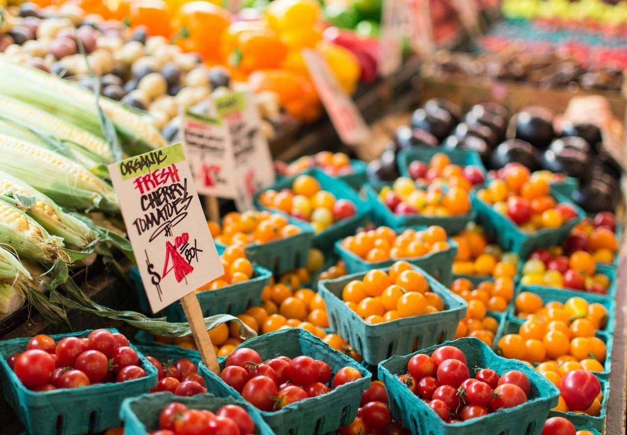 Farmers market tomatoes and corn with handwritten price sign