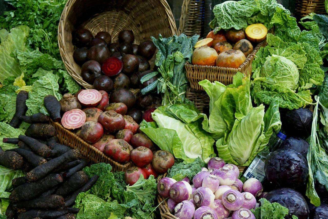 Overhead spread of dark carrots beets and cabbages in baskets
